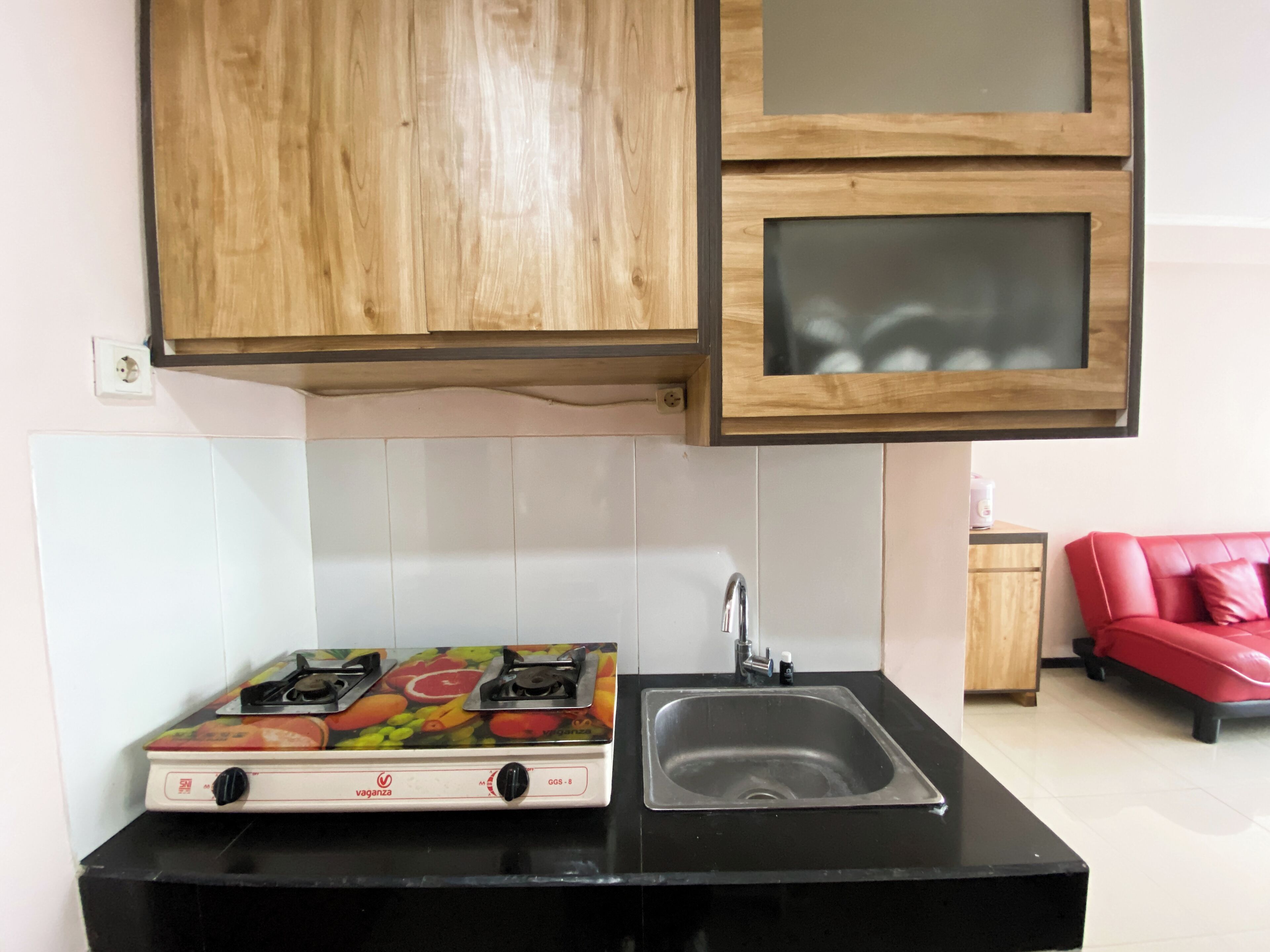 Een keuken met een gasfornuis, een spoelbak en houten keukenkastjes.