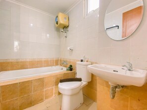 Bathroom features a bathtub, toilet, and sink, with a window above the bathtub and a mirror above the sink.