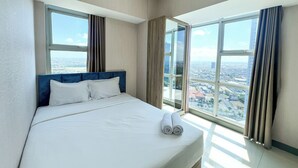 Une chambre d’hôtel avec un grand lit, deux fenêtres et une vue sur la ville.