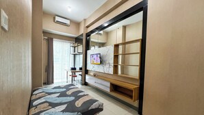 A bedroom with a bed, a TV mounted on a wall, a desk, and a chair.