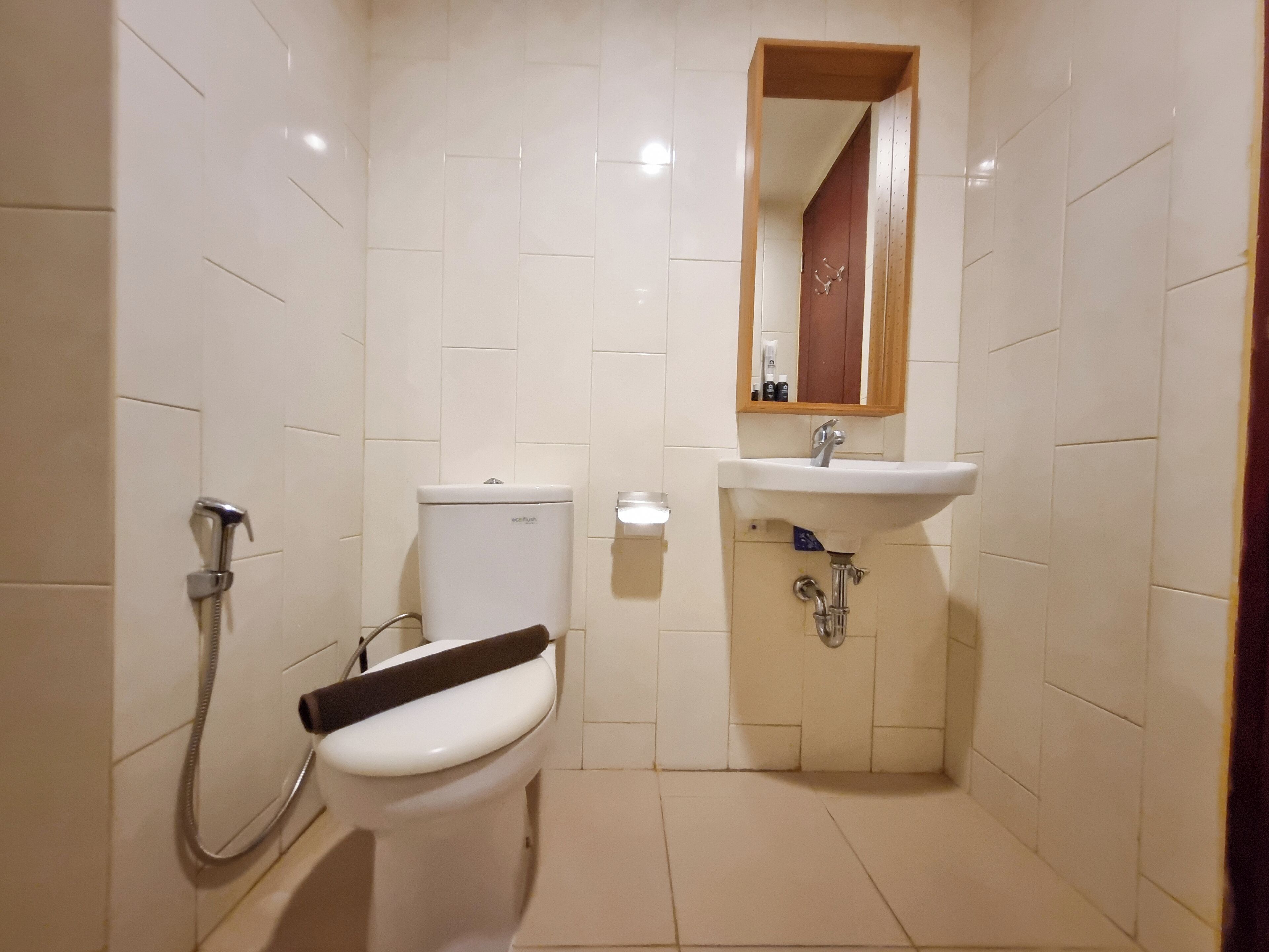 Une petite salle de bain propre, équipée de toilettes, d’une douche et d’un lavabo.