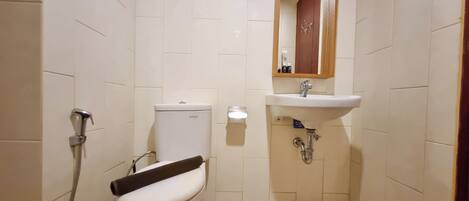 Une petite salle de bain propre, équipée de toilettes, d’une douche et d’un lavabo.