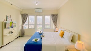 A hotel room with a bed, a desk, a TV, and a window with curtains. - Comfort Studio (No Kitchen) At Grand Palace Kemayoran Apartment (Free Ipl & Utilities) (Jakarta)