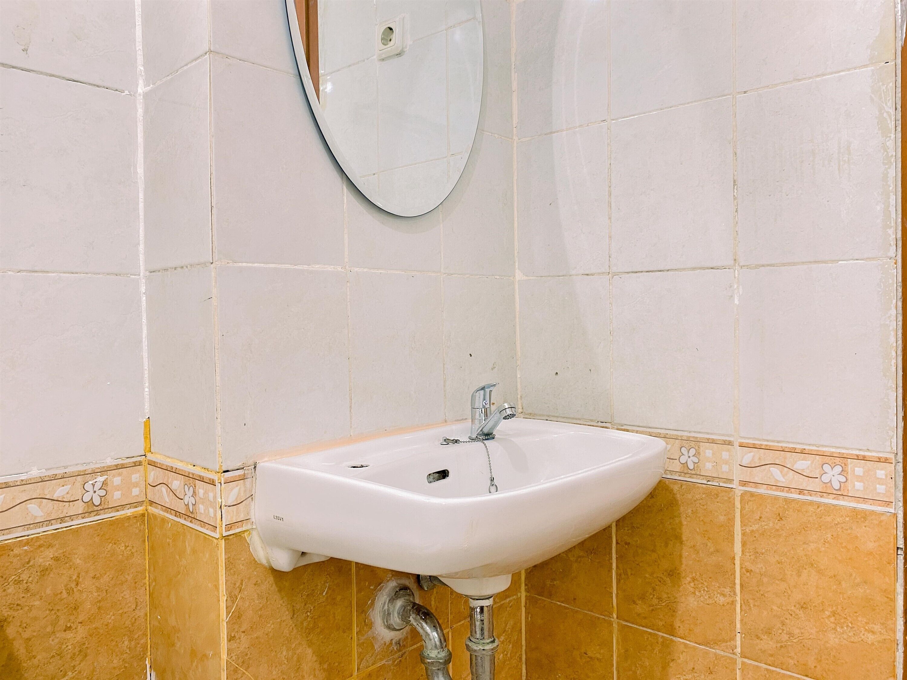 A bathroom with a white sink, a mirror, and tiled walls.