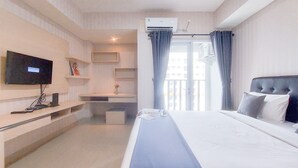 Une chambre d’hôtel avec un lit, une télévision, un bureau et une fenêtre avec des rideaux.