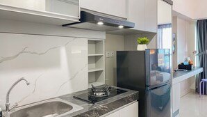 A modern kitchen with a stainless steel sink, black refrigerator, and a gas stove. - Best Place And Restful Studio At Apartment Springlake Summarecon Bekasi (Bekasi)