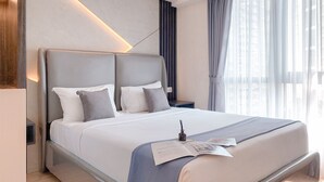 A modern hotel room with a large bed, a bedside table, and a window with curtains. - Best Place And Wonderful 3Br Apartment Sky House Bsd Near Aeon Mall (Pagedangan)