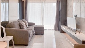 A modern living room with a sofa, a TV, and a marble wall. - Best Place And Wonderful 3Br Apartment Sky House Bsd Near Aeon Mall (Pagedangan)