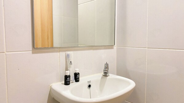 Ein Badezimmer mit einem weißen Waschbecken, einem Spiegel darüber und Toilettenartikeln auf dem Waschbecken.