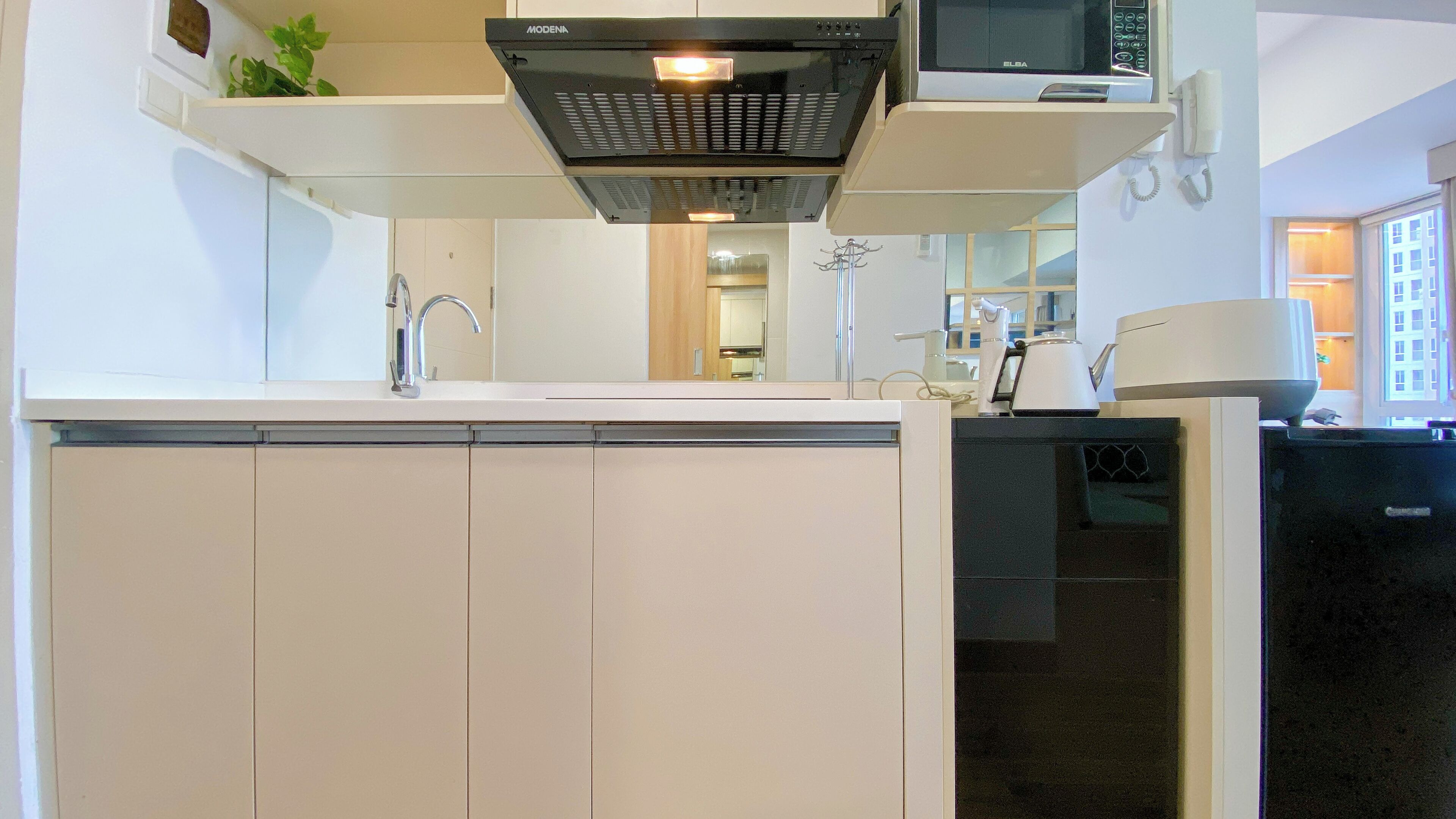 A modern kitchen with white cabinetry, a built-in microwave, and a range hood above the stove.