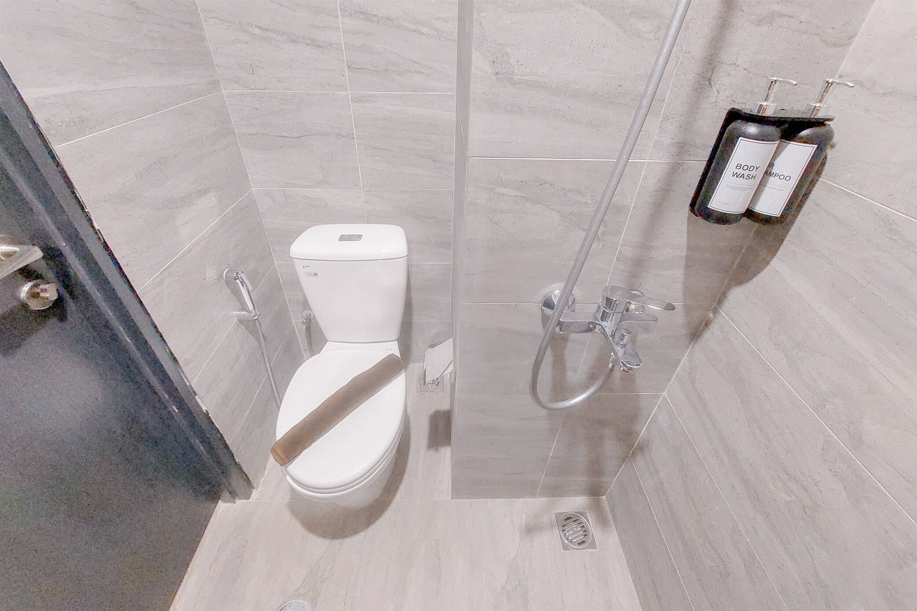A modern bathroom with a toilet, shower, and a shelf with toiletries.