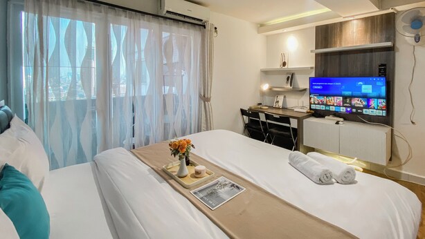 Hotellihuone, jossa on sänky, työpöytä, televisio ja ilmastointilaite.