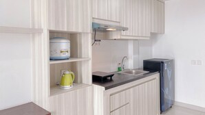 Una cucina moderna con mobili chiari in legno, un lavello in acciaio inossidabile, un frigorifero nero e un bollitore sul piano di lavoro.