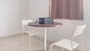 Un tavolino piccolo e rotondo con una scatola scura e due sedie bianche.