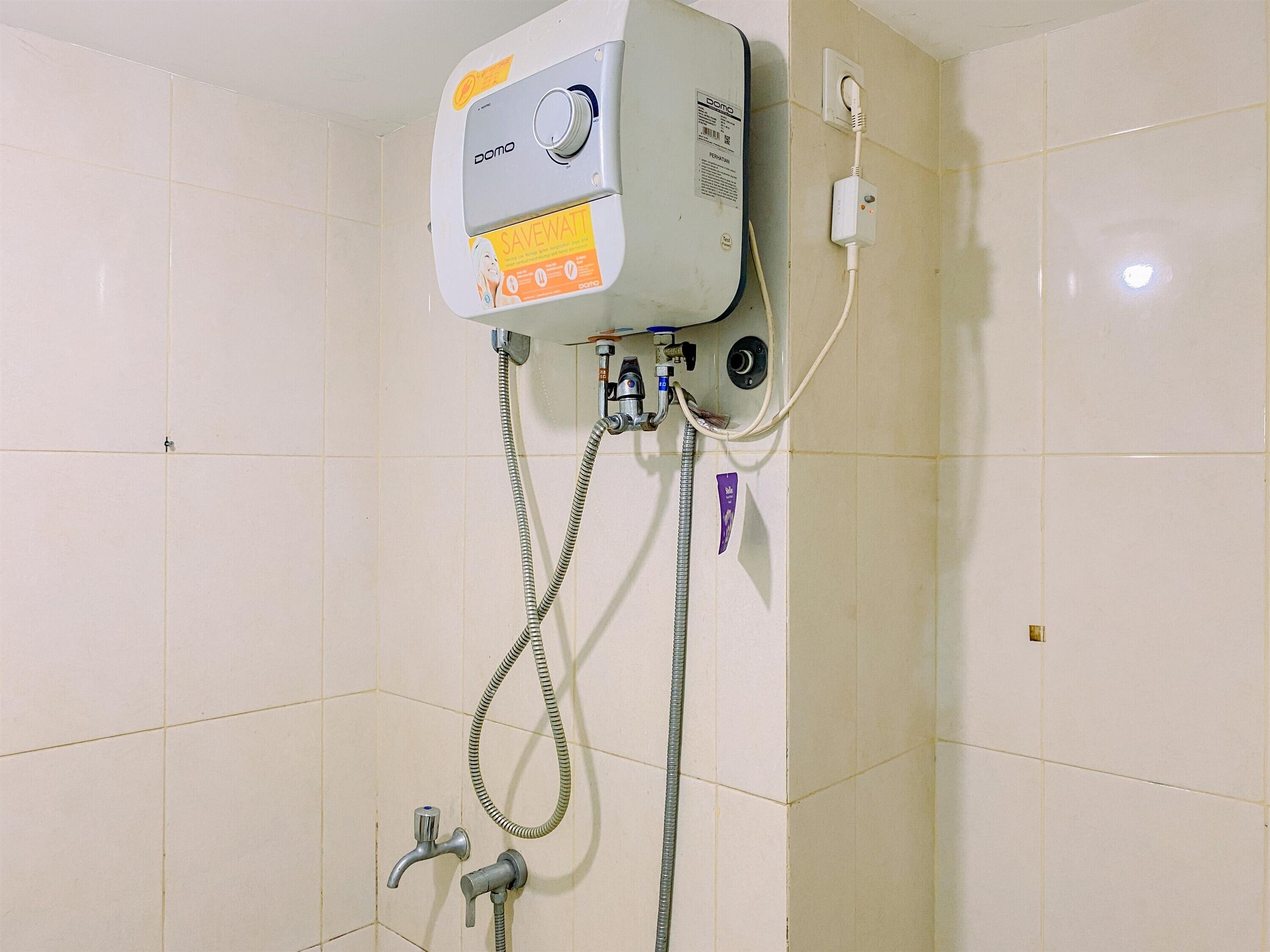 A shower unit with a control panel, a handheld showerhead, and a wall-mounted faucet.