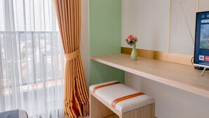A hotel room with a bed, a bench, a small table with a vase of flowers, and a TV on a stand.