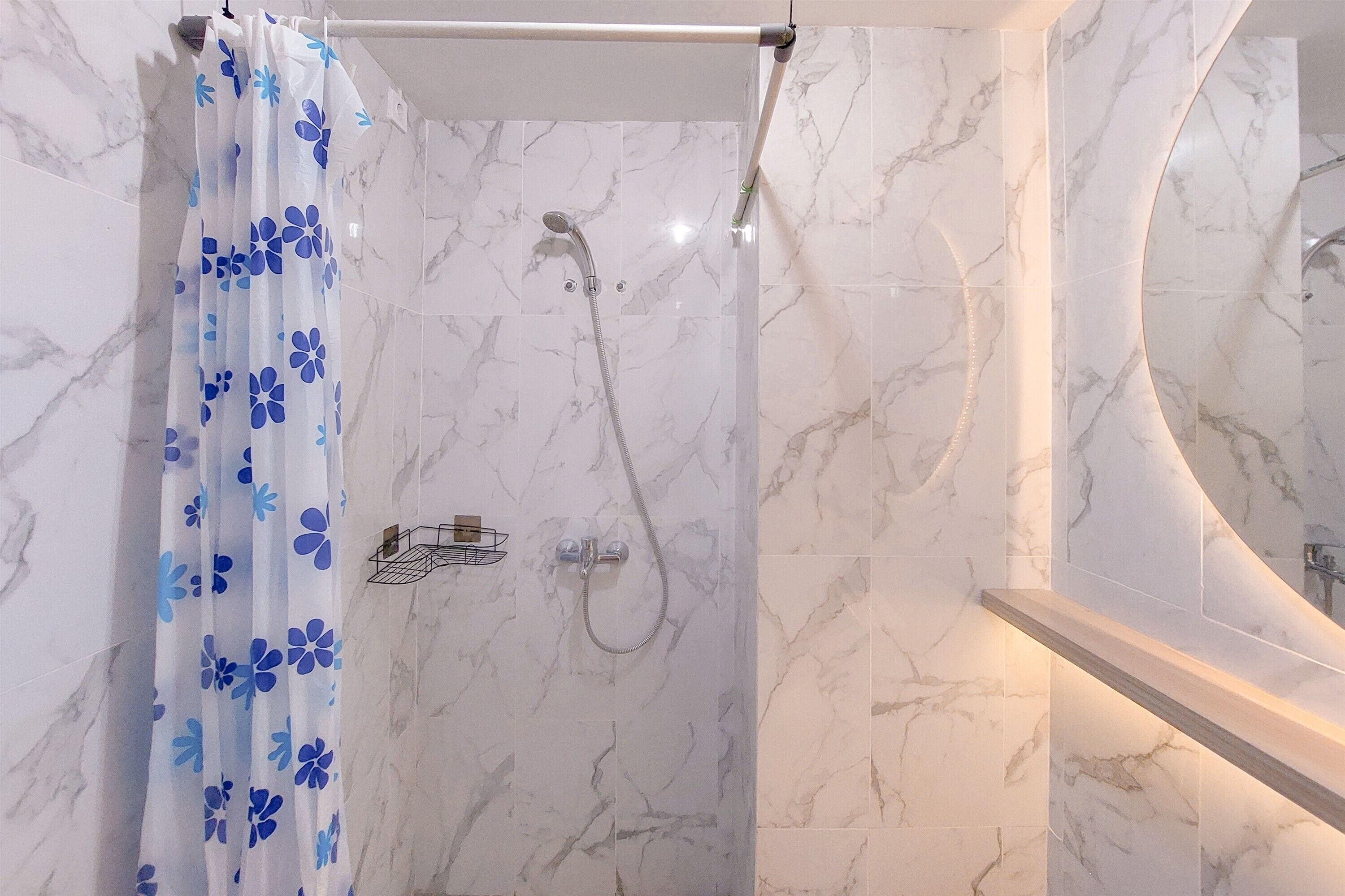 Une salle de bain avec une douche, des murs en marbre et un miroir.