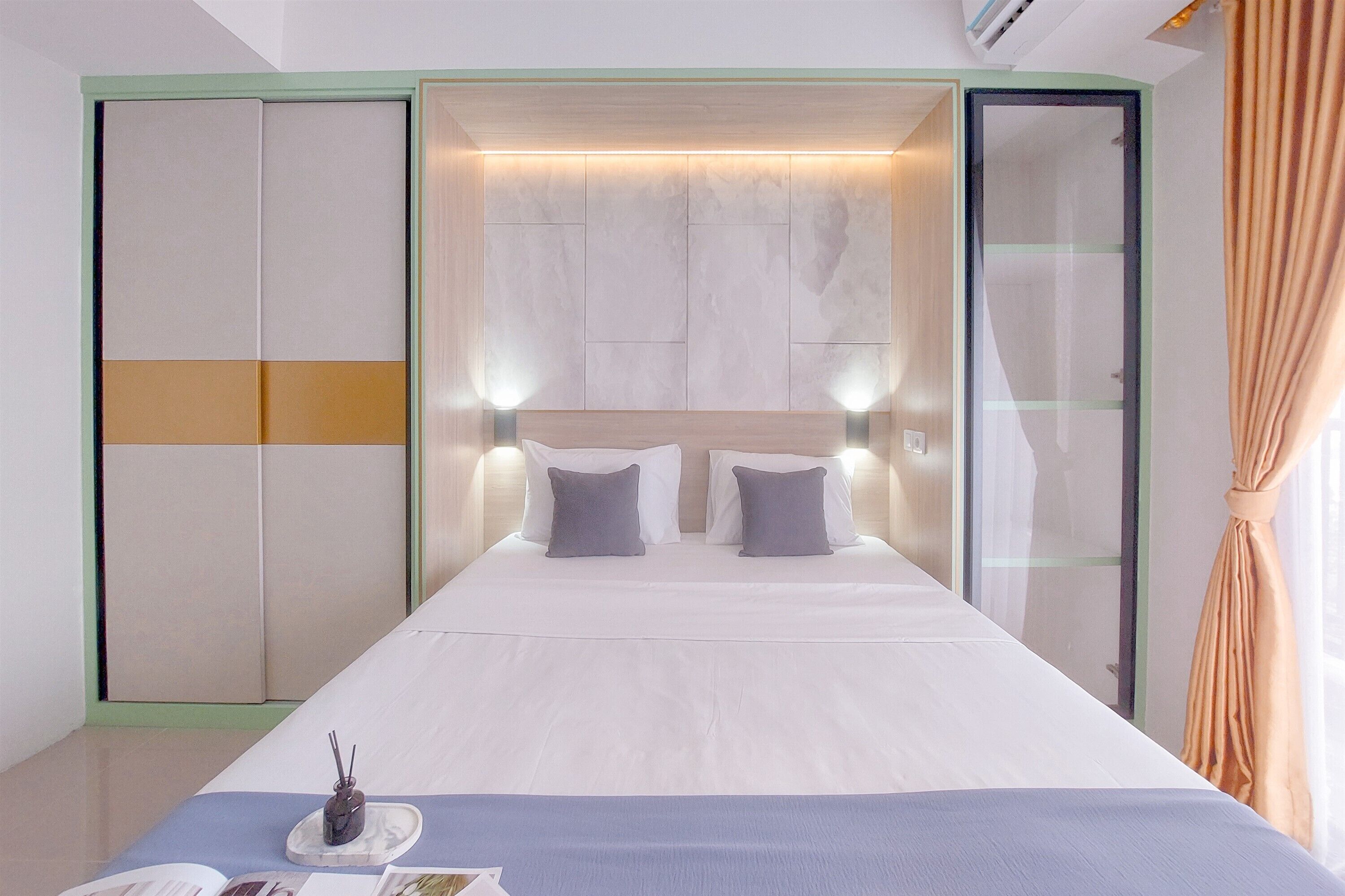 A modern hotel room with a large bed, bedside tables, and a wardrobe.