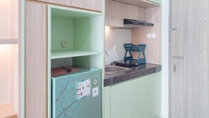 A compact kitchen with a built-in refrigerator, a sink, and a microwave.