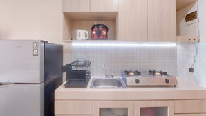 Una cocina compacta con refrigerador, estufa, lavamanos y microondas.