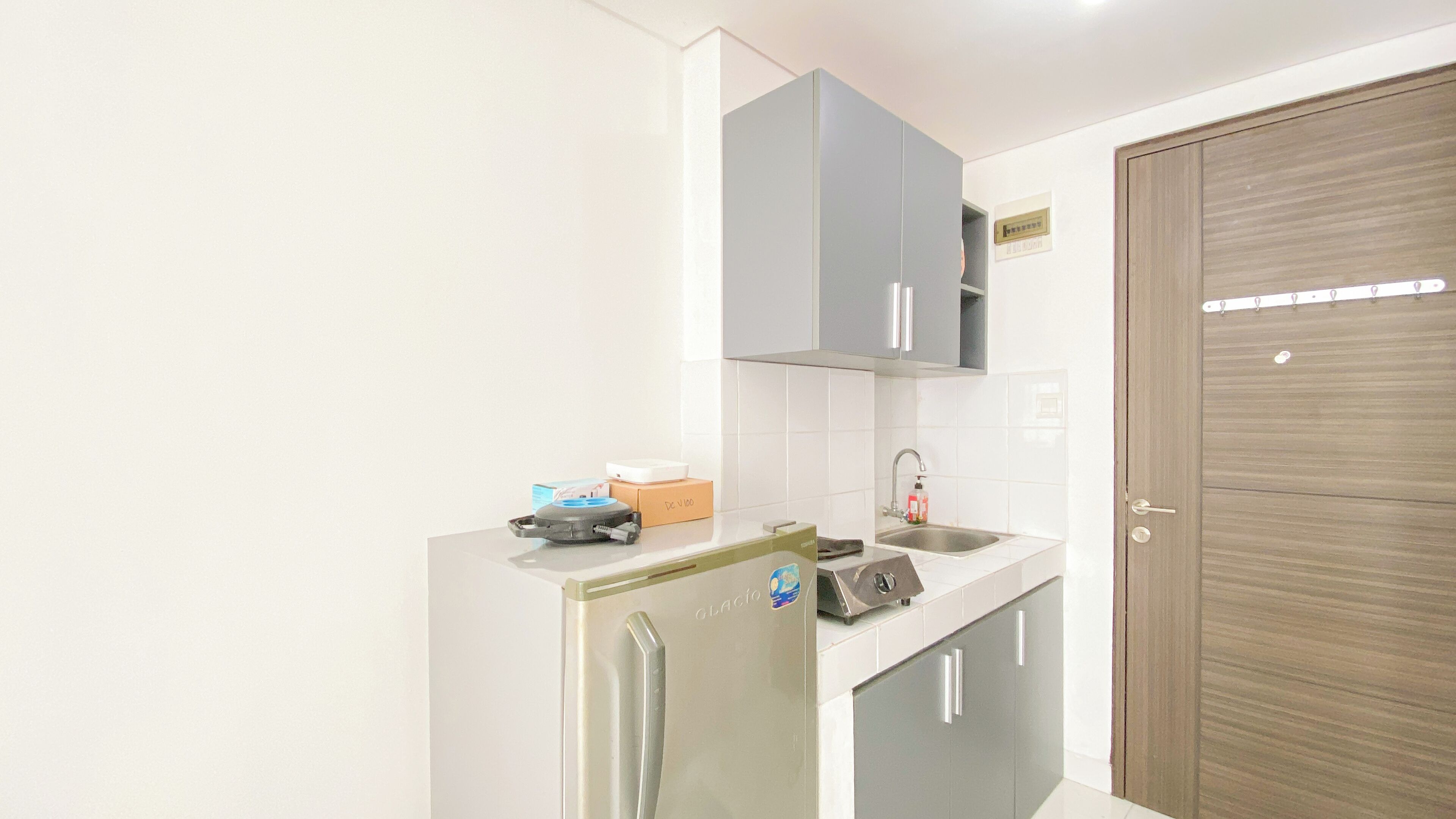 A compact kitchen with a refrigerator, a sink, and cabinets.