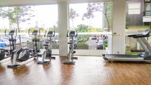 A gym with cardio machines, large windows, and a view of a parking lot. - Spacious And Elegant 1Br At Apartment Silkwood Residence (Tangerang)