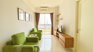 A modern living room with a green sofa set, a wooden console table, and a television. - Spacious And Elegant 1Br At Apartment Silkwood Residence (Tangerang)
