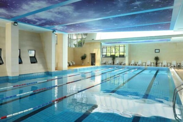 A swimming pool with lanes, a ceiling mural, and a sunlit room with chairs and a plant. - Jinpeng Eco Hotel (Dengfeng)