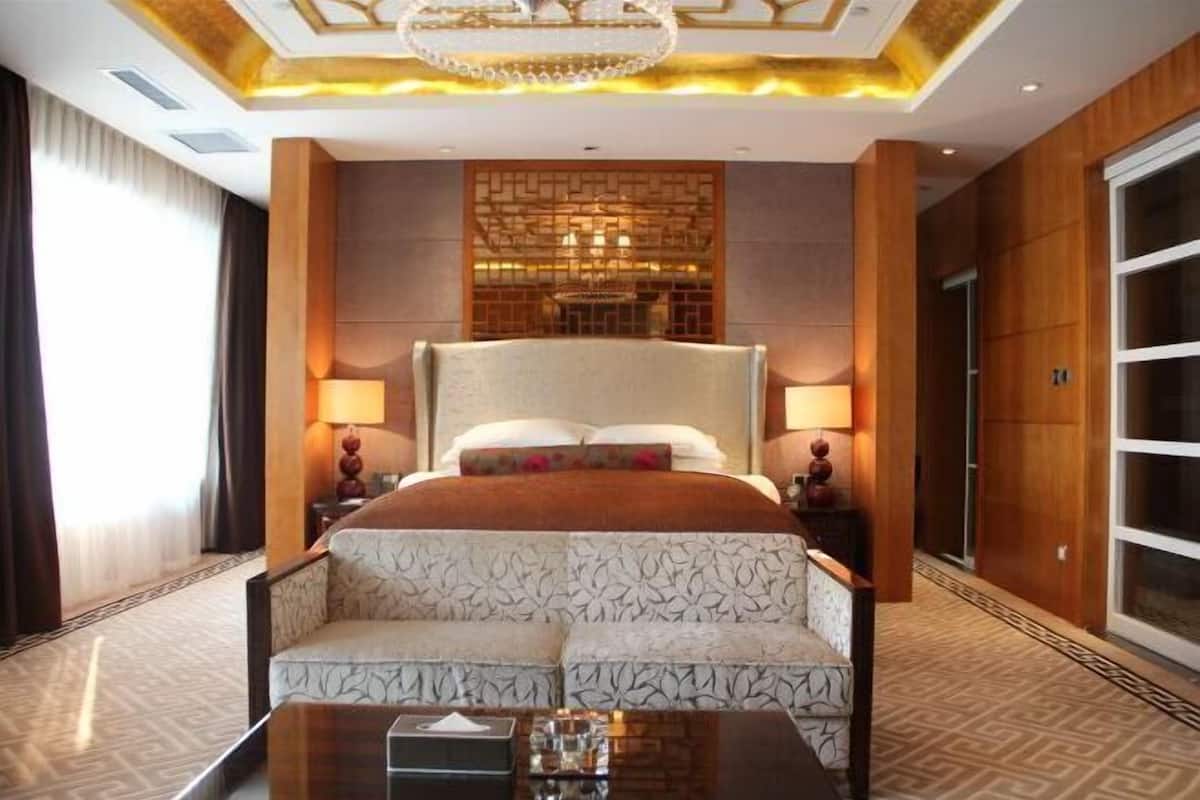 Ein Hotelzimmer mit einem großen Bett, zwei Nachttischlampen, einem Sofa, einem Couchtisch und einer dekorativen Deckenleuchte.