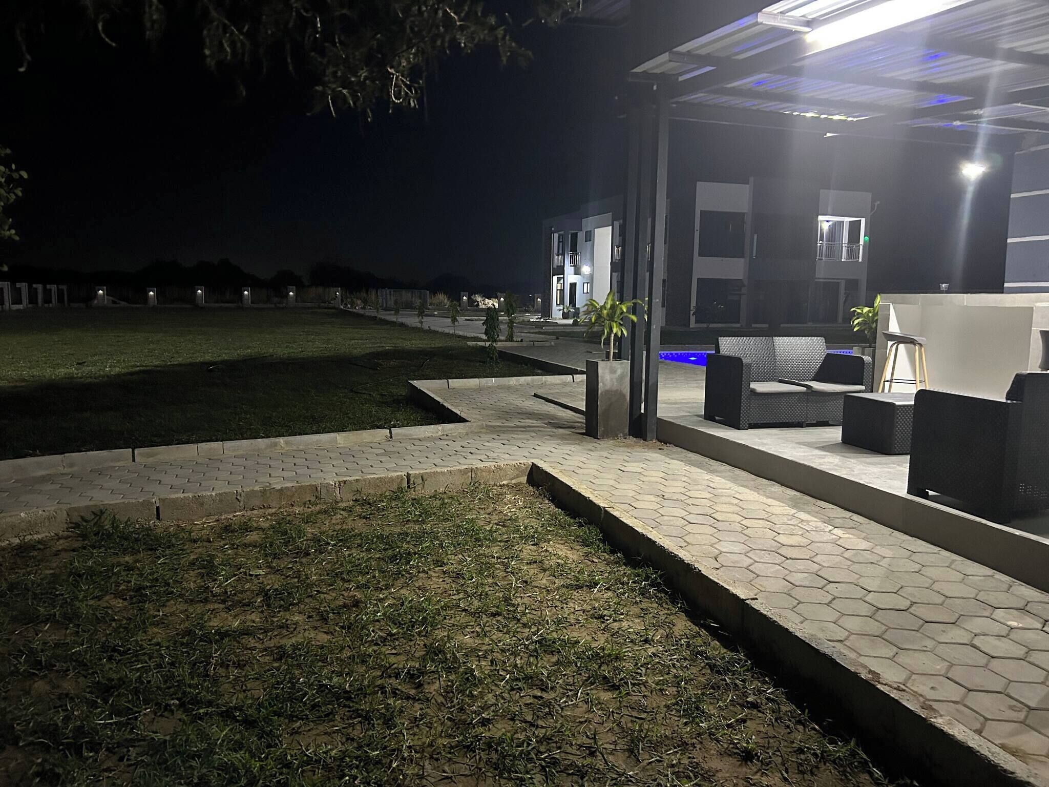 Een terras met honingraatbestrating, een gazon en een gebouw met een modern ontwerp op de achtergrond.