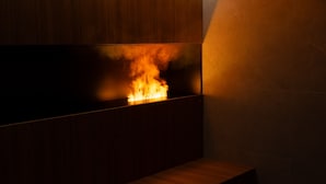 A modern interior with a built-in fireplace, a wooden bench, and a tiled wall. - Arbed Living Hotel (Arbedo-Castione)