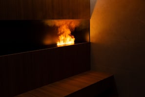 A modern interior with a built-in fireplace, a wooden bench, and a tiled wall. - Arbed Living Hotel (Arbedo-Castione)