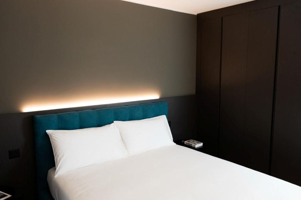 Una camera d'albergo con un letto, un comodino e una lampada a parete.