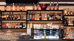 A bar area with shelves of liquor bottles, a coffee machine, and a sign that reads "My Way". - Arbed Living Hotel (Arbedo-Castione)