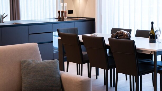 A modern living room with a sofa, dining table, and chairs. - Arbed Living Hotel (Arbedo-Castione)