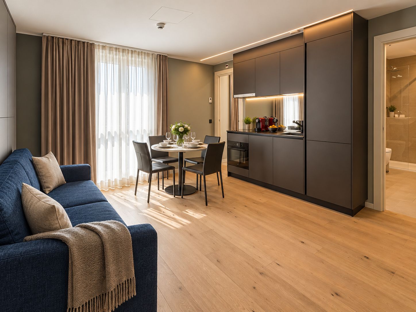 A modern living room with a sofa, dining table, and kitchen area.