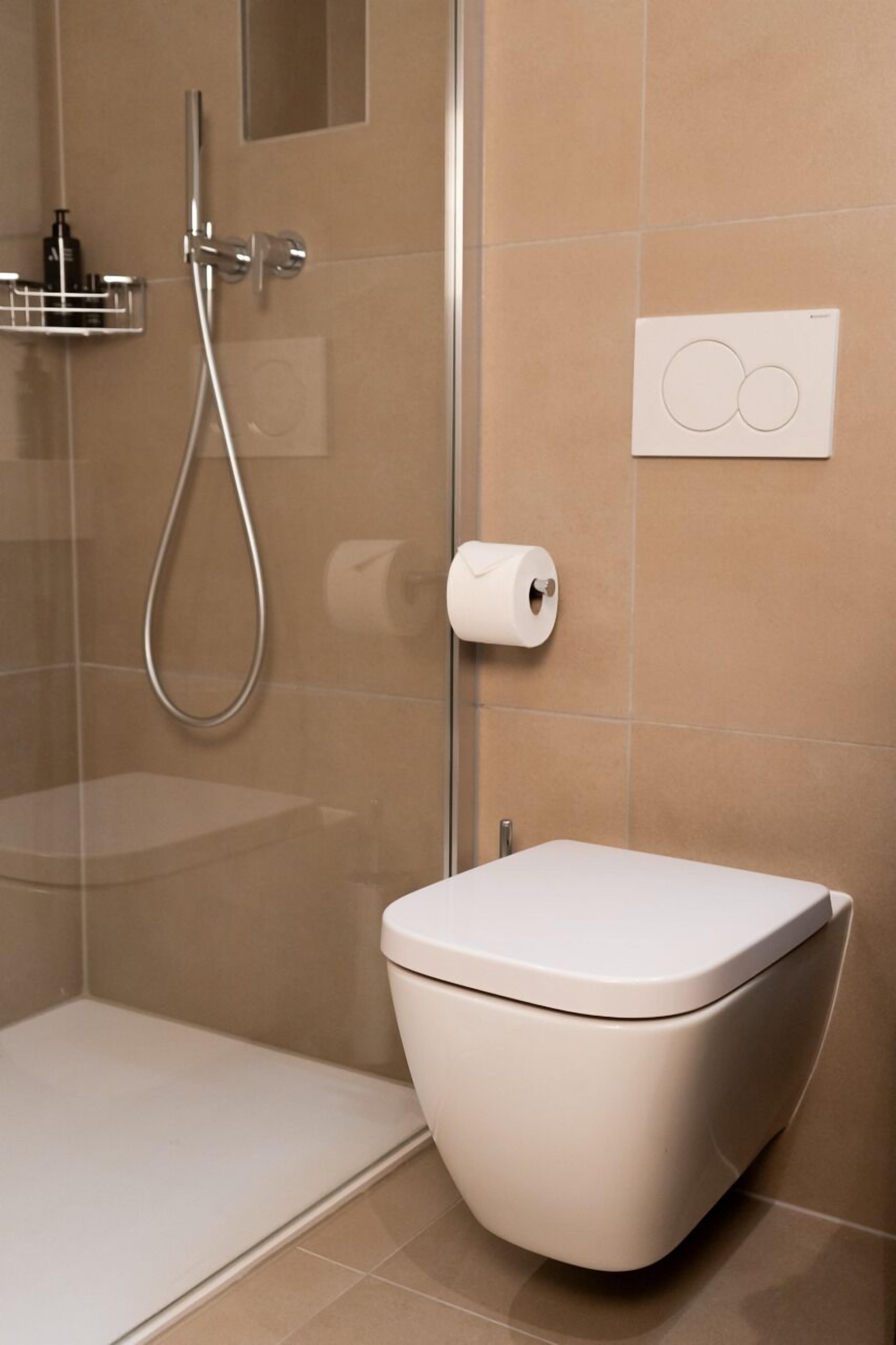 Ein modernes Badezimmer mit Toilette, Glasdusche und Handtuchhalter.