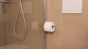 Ein modernes Badezimmer mit Toilette, Glasdusche und Handtuchhalter.
