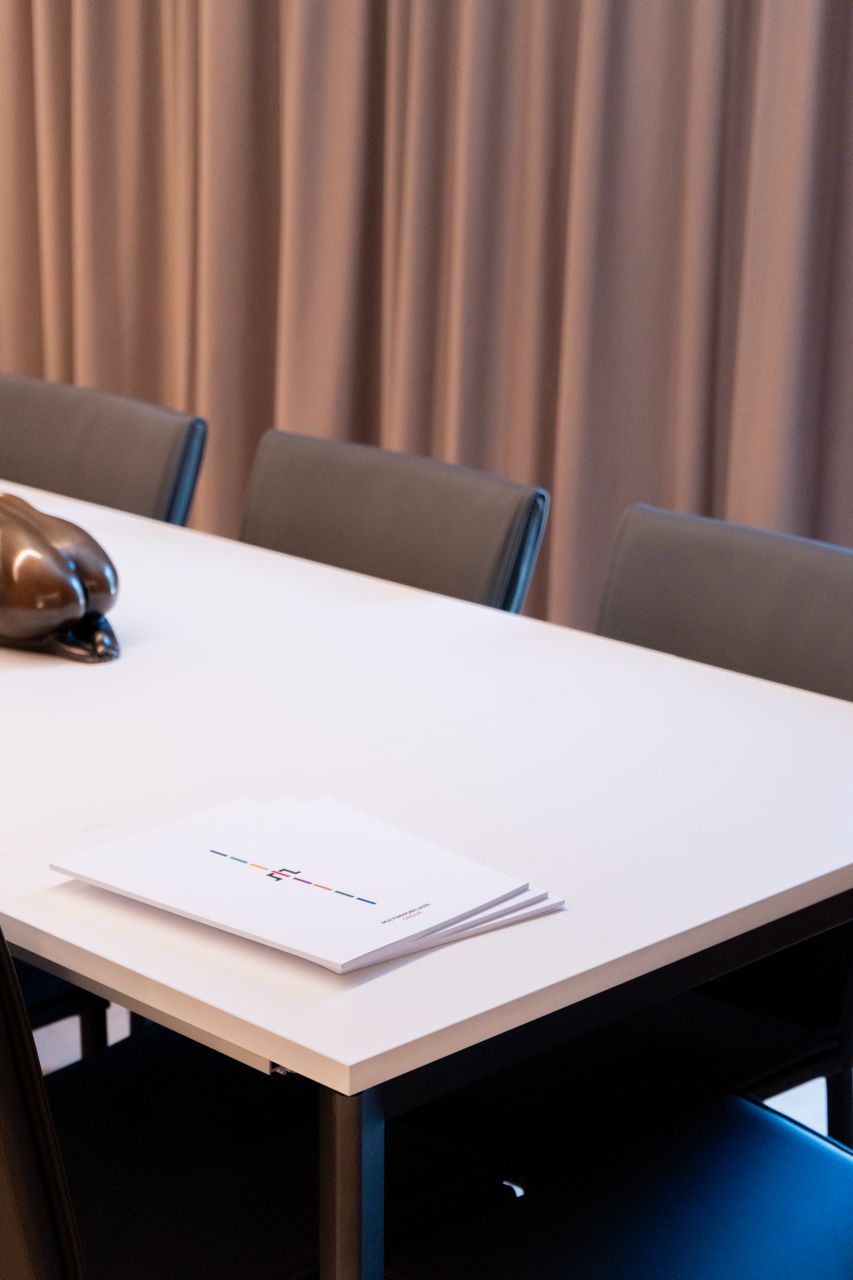 Une table de conférence avec des documents, un ordinateur portable et un objet décoratif.