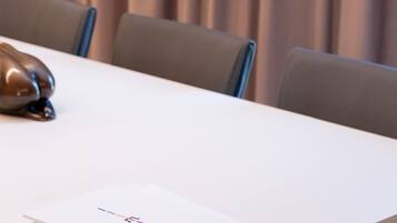 Une table de conférence avec des documents, un ordinateur portable et un objet décoratif.