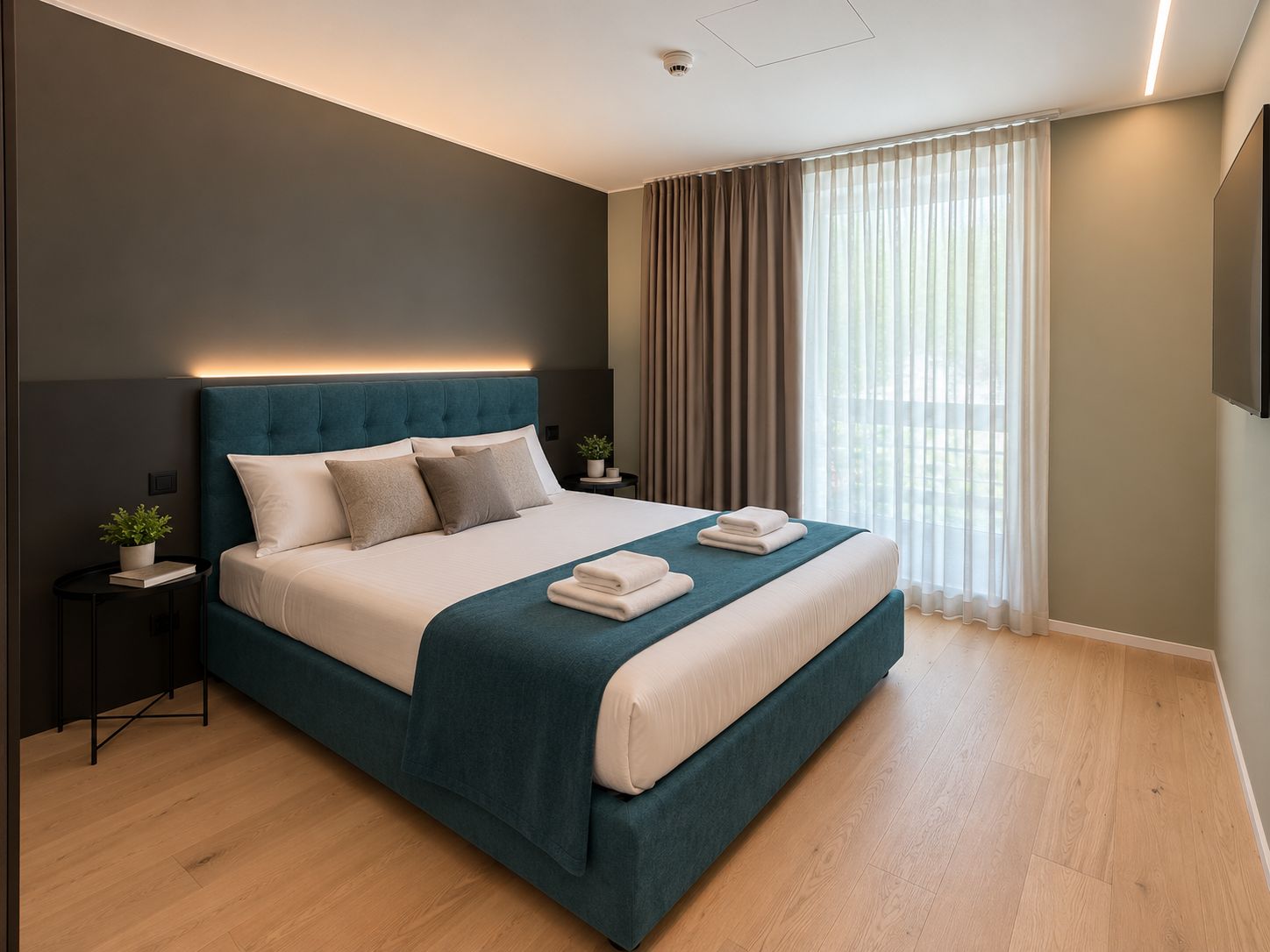 A modern bedroom with a large bed, bedside tables, a flat-screen TV, and a window with curtains.
