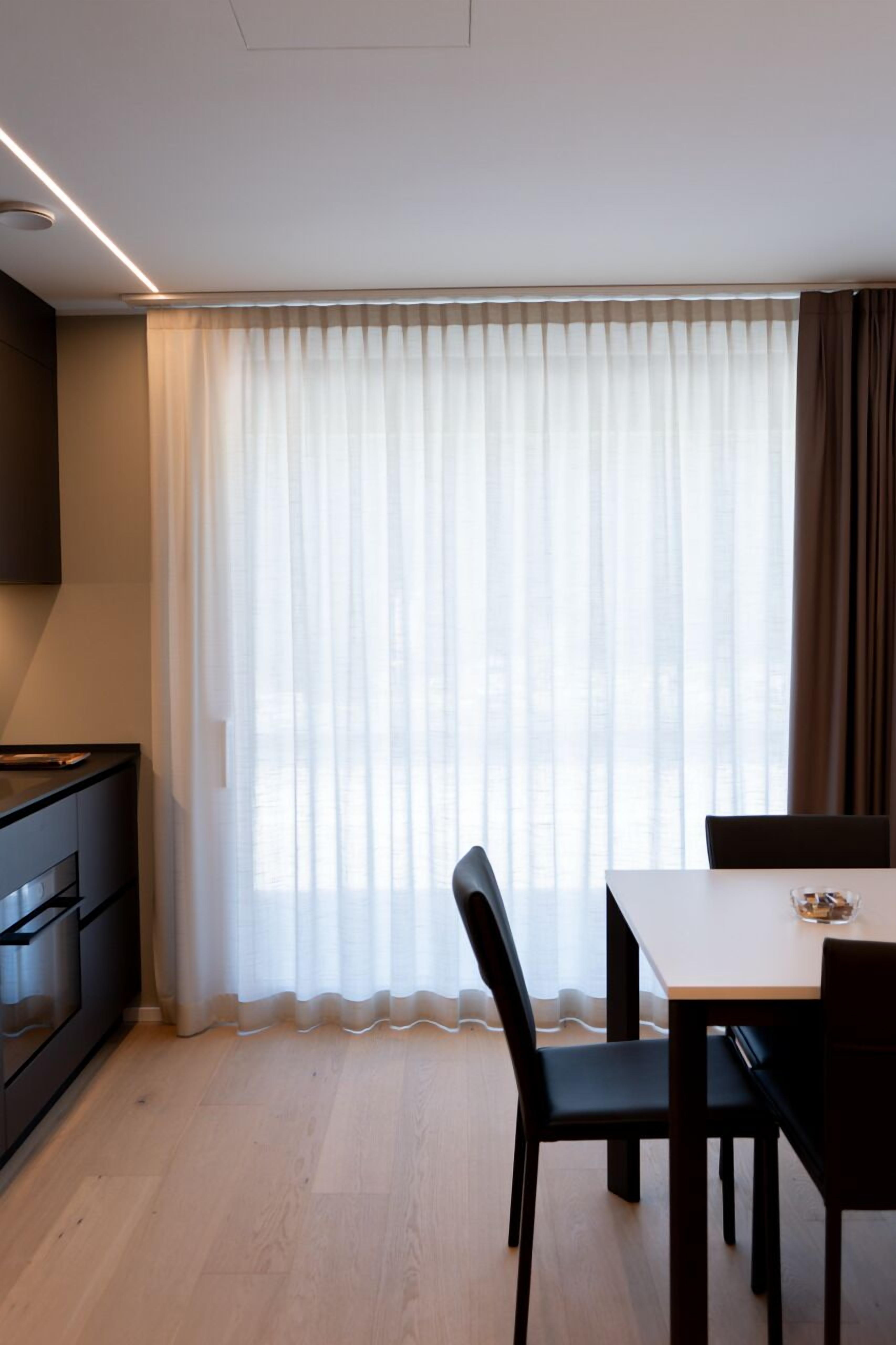 Eine moderne Küche mit Einbauofen und Essbereich mit Tisch und Stühlen.
