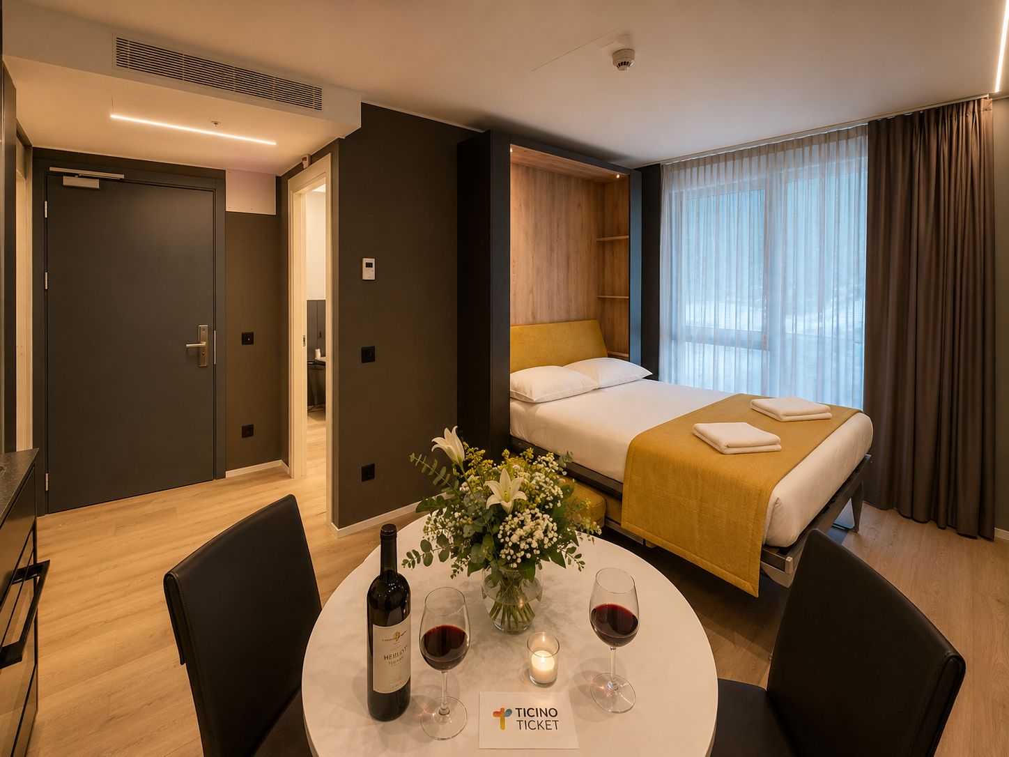 Ein Hotelzimmer mit einem Bett, einem Tisch mit einer Weinflasche, Gläsern und einer Kerze.