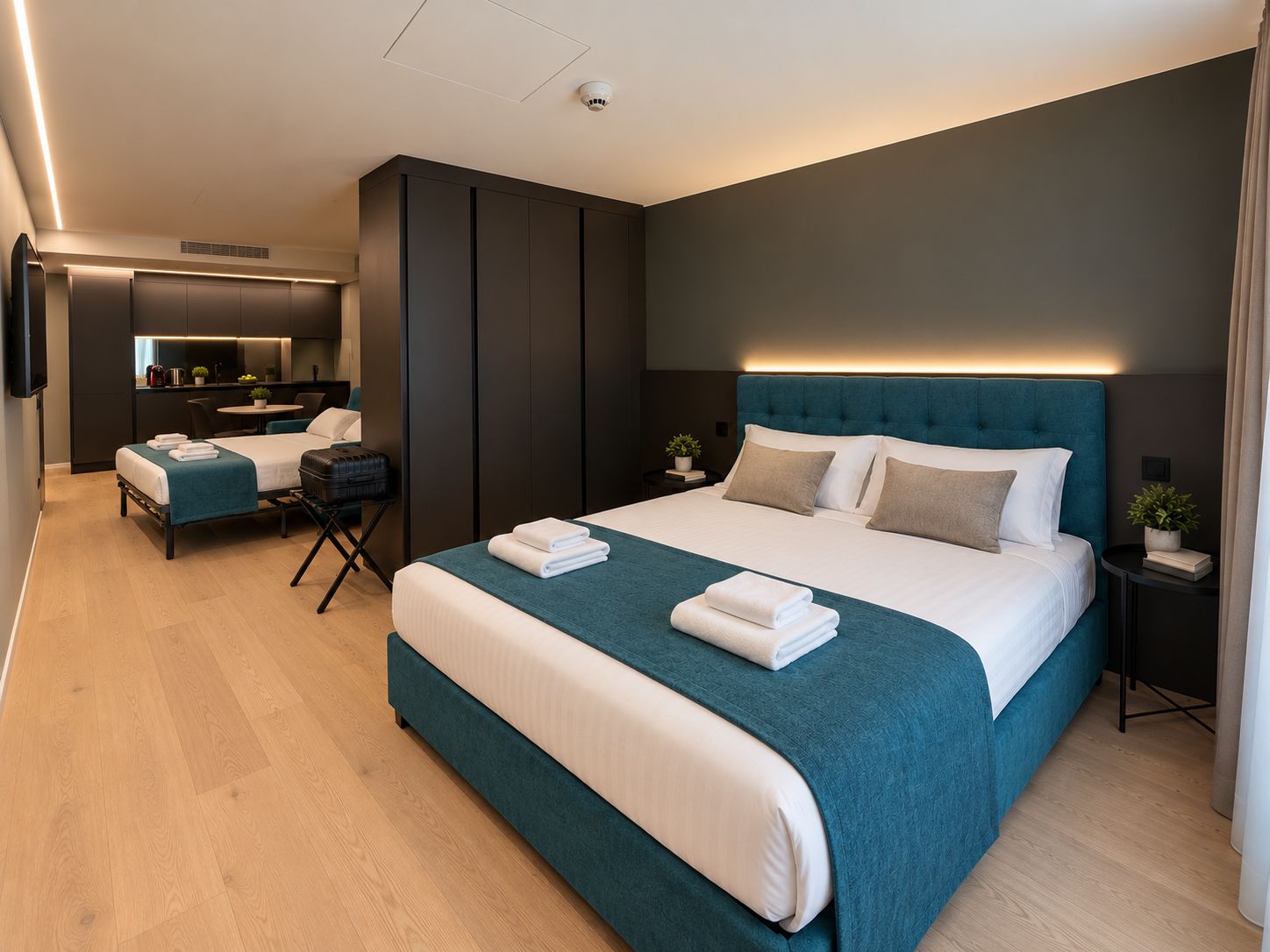A modern hotel room with a large bed, a desk, a chair, and a small table.