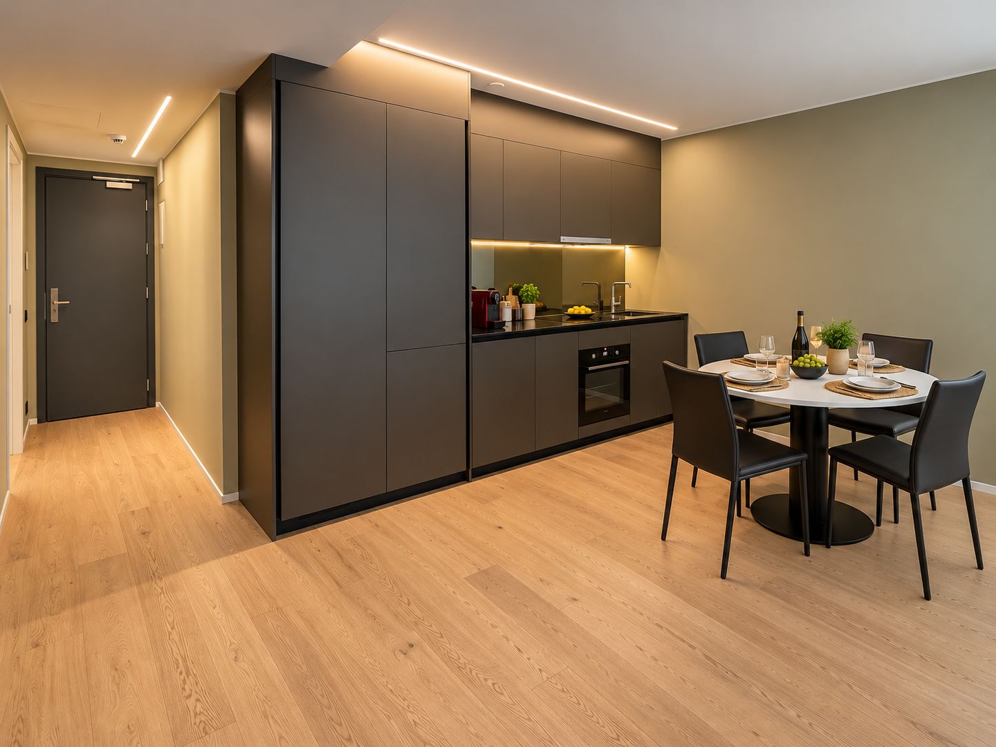 Una cucina moderna con elettrodomestici integrati, una zona pranzo con tavolo e sedie rotonde, e un corridoio con una porta.