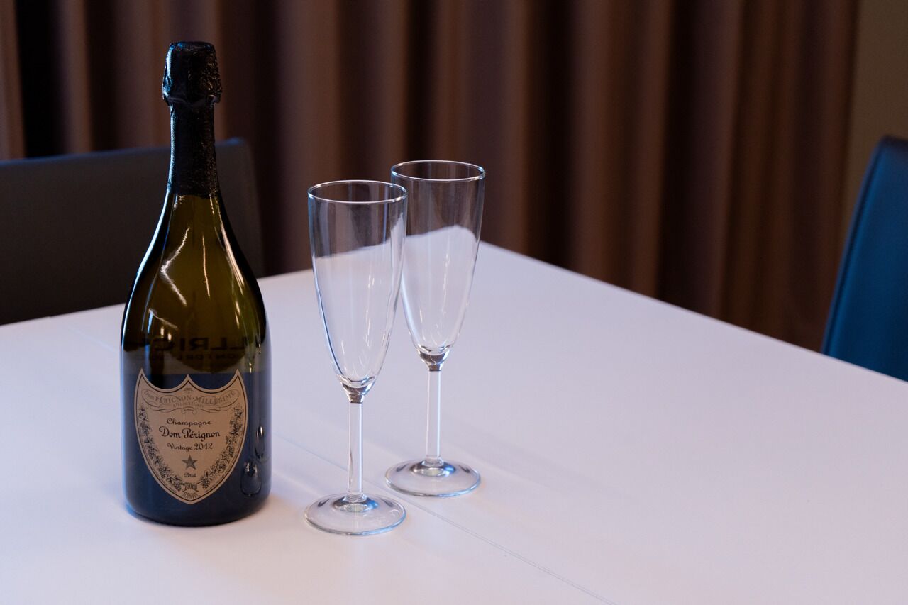 A bottle of champagne and two glasses on a white table.