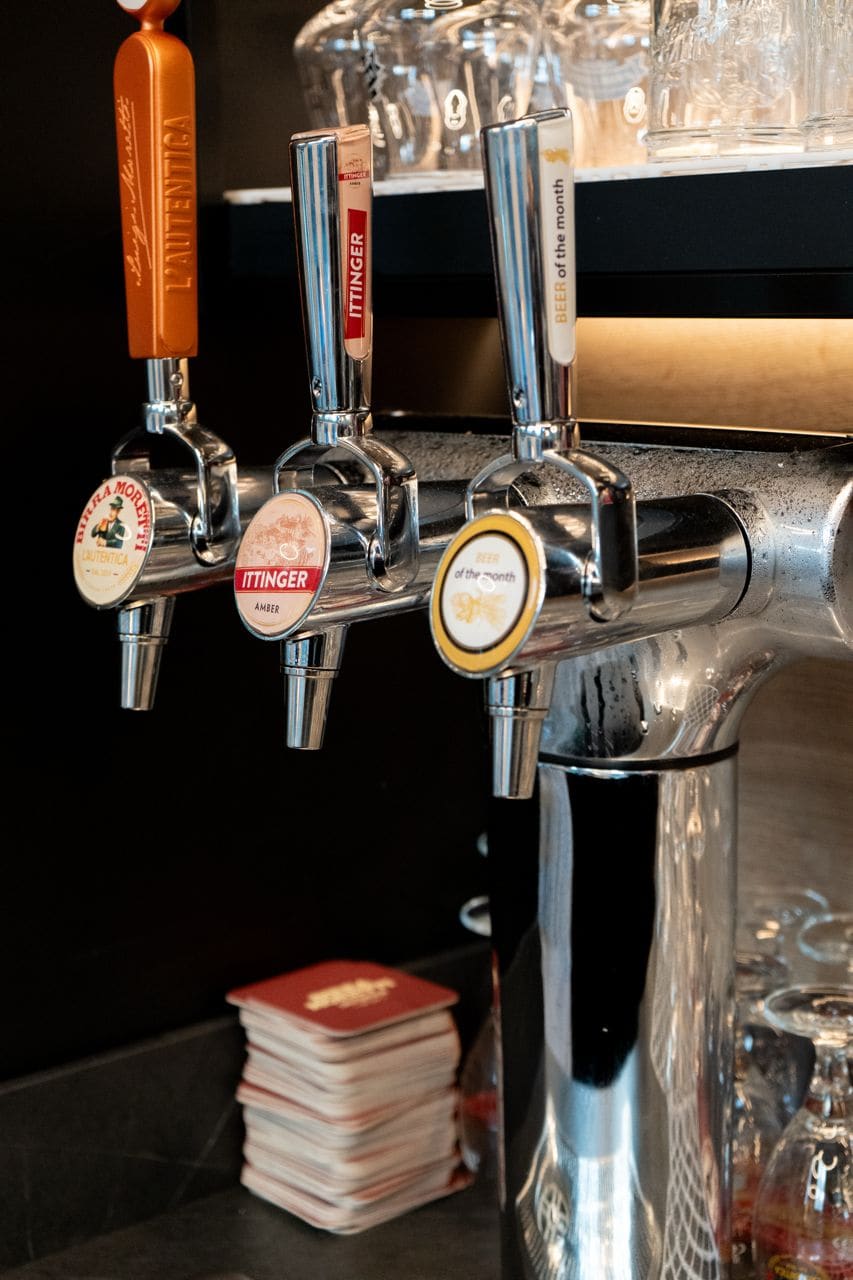 Un impianto di erogazione di birra con numerosi rubinetti, tra cui marchi come L'Authentica e Itinger.