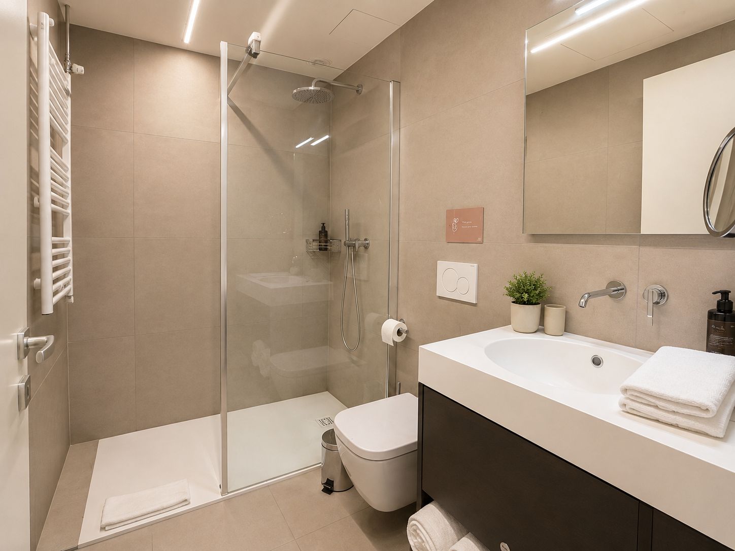 Ein modernes Badezimmer mit einer in Glas eingefassten Dusche, einem weißen Waschbecken und einer Toilette.