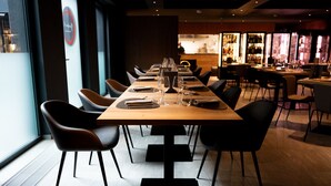 A restaurant with a long wooden table set for dining, surrounded by black chairs. - Arbed Living Hotel (Arbedo-Castione)