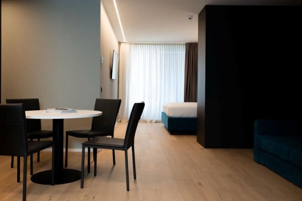 Ein modernes Hotelzimmer mit Essbereich, einem Bett und einem blauen Sofa.